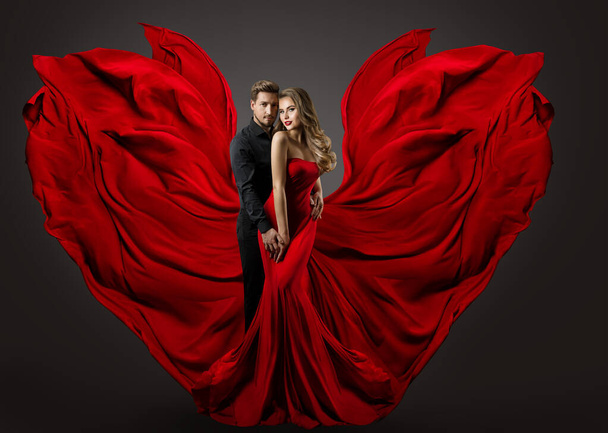 Fashion Couple in Love. Woman in fantasy long Red Gown and handsome Man. Flying Silk Fabric as Wings. Studio Portrait - Foto, immagini