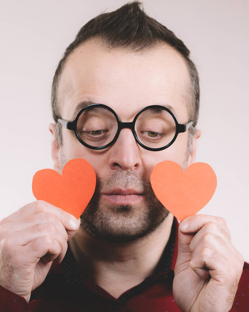 Adult serious man holding two red hearts. Romance love valentines day concept. - Valokuva, kuva