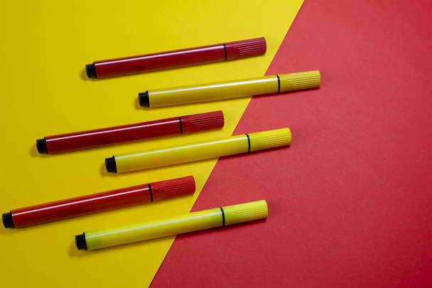 Composición creativa de dos colores con rotuladores rojos y amarillos. Seis nuevas plumas de fieltro de color sobre un fondo rojo y amarillo. - Foto, Imagen