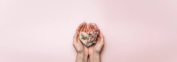 Flat lay of woman hands holding wooden heart on soft color background - Foto, Bild