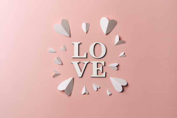 Creative flat lay of word love on soft color  background with paper hearts.  - Foto, afbeelding
