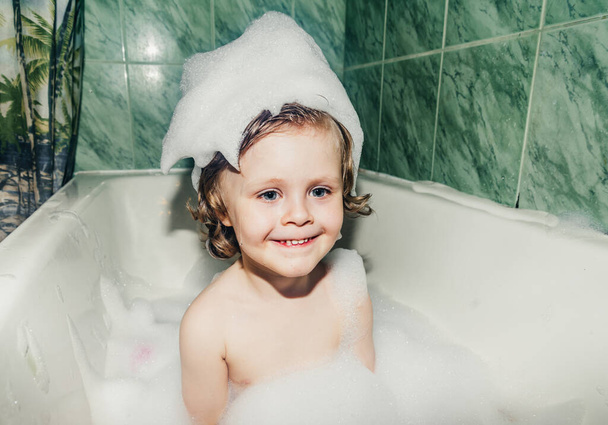 красивый ребенок малыша сын моет в ванной играет весело с мыльными пузырями, пены - Фото, изображение
