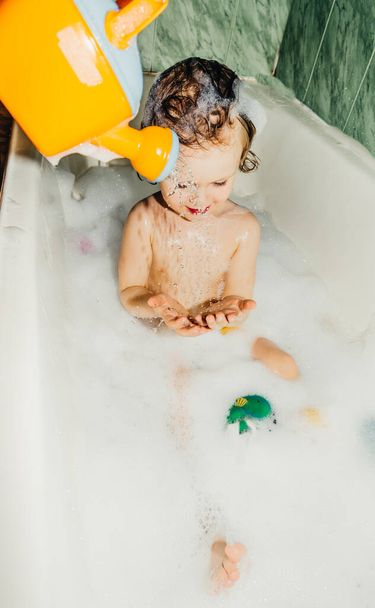 gyönyörű gyermek kisgyermek kisgyermek mossa a fürdőszobában játszik szórakozik szappanbuborékok, hab - Fotó, kép
