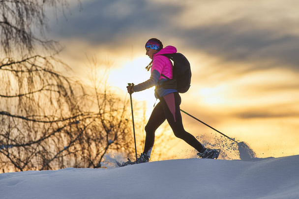 Einsames Mädchen wandert mit Schneeschuhen bei Sonnenuntergang - Foto, Bild