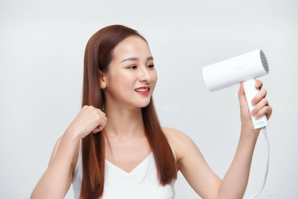 Beautiful Smiling Woman Drying Healthy Long Straight Hair Using Hair Dryer. - Foto, afbeelding