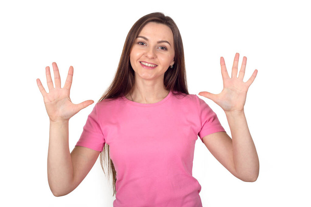 Young woman in a pink sweater shows 10 fingers as the number ten. - Foto, imagen