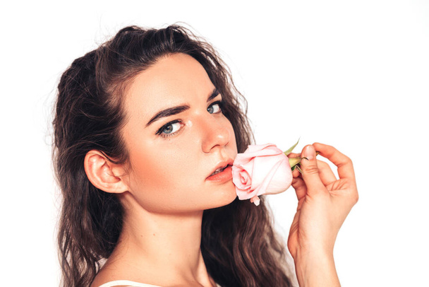 Young woman on white background with pink roses near her lips. face care. oil, lip balm. - Foto, imagen