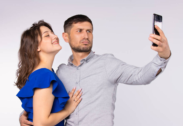 Authentic couple make selfie on smartphone. Gray background. Spending time concept. Technologies. - Fotó, kép