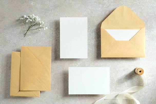 Wedding invites and stationery top view. Blank paper cards mockups, kraft paper envelopes, ribbon, flowers on stone table. Vintage style. Flat lay. - Valokuva, kuva