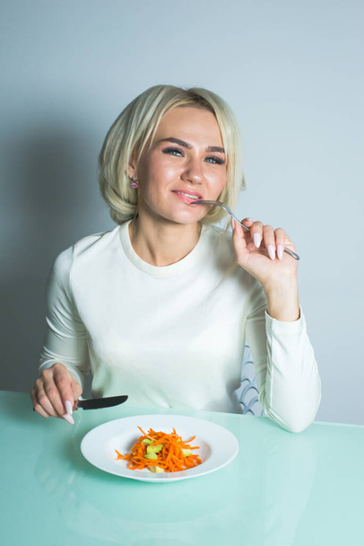 Девушка сидит за столом и ест здоровый салат. - Фото, изображение