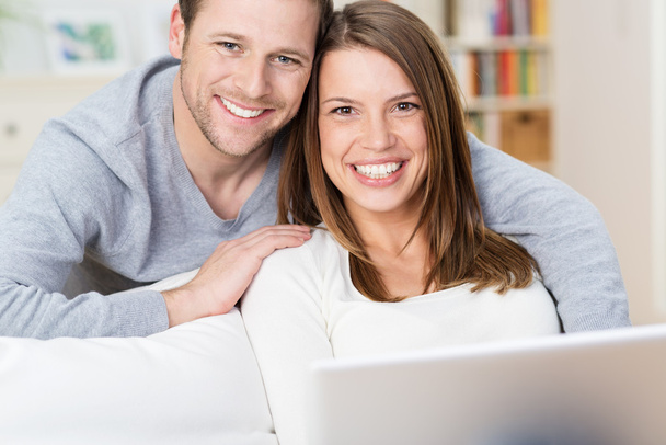 Smiling young couple sharing a laptop computer - 写真・画像