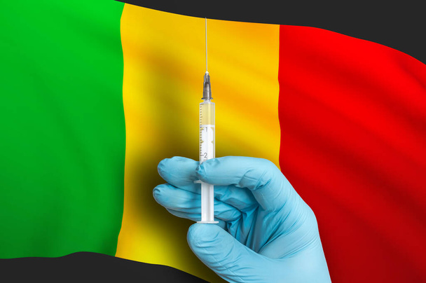 Impfungen in Mali. Impfstoff zum Schutz vor Covid-19 auf dem Hintergrund der Nationalflagge. - Foto, Bild
