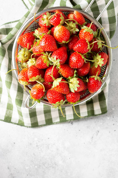 Strawberry. Strawberries in a metal bowl on a light gray background. Lots of strawberries. Top view with copyspace - Photo, Image