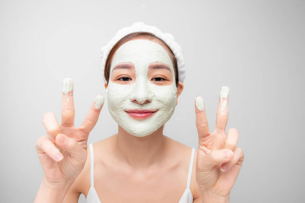 Attraactive young Asian woman with a face clay mask against acne on the face of a woman to rejuvenate the skin - Fotó, kép