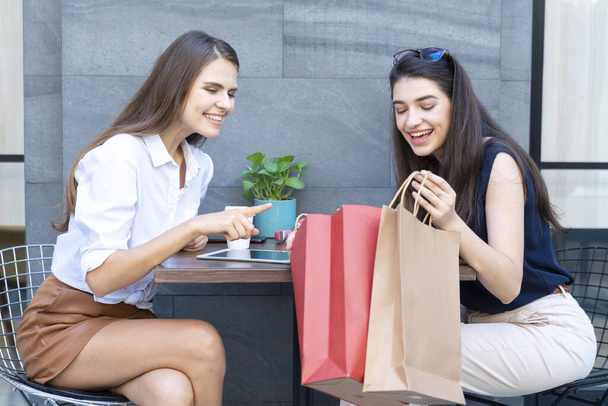 Consumer concept. Young women carry shopping bags. Happy woman paying in cafe by credit card and smart phone. Woman took a contactless payment. People, finance, - Foto, Bild