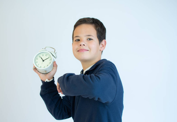 School boy showing alarm clock. Isolated on white background. - Foto, afbeelding