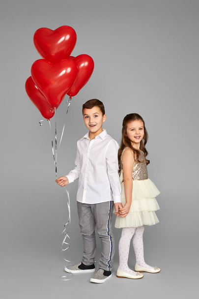 couple of little girl and boy with red heart balloons - Фото, зображення
