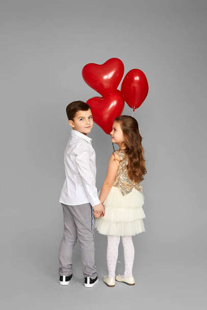 couple of little girl and boy with red heart balloons - Foto, Bild