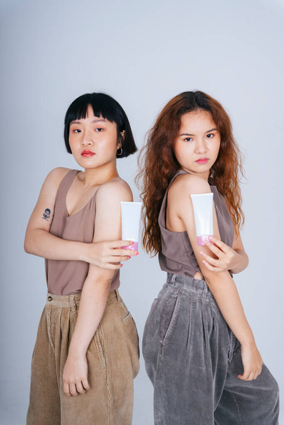 Porträt zweier junger asiatischer Frauen mit Lotionflasche für die Hautpflege. - Foto, Bild