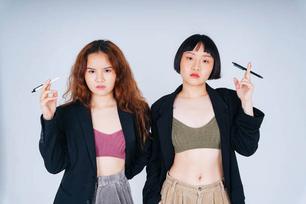Portret van twee jonge Aziatische zakenvrouwen in zwart jaspak met een pen op witte achtergrond. - Foto, afbeelding