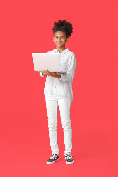 Teenage African-American girl with laptop on color background - Photo, Image