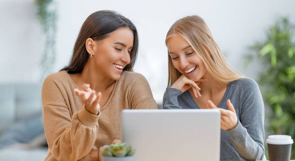 Two happy young women using laptop. Friends spending time together. - Photo, Image