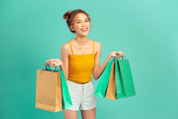 Happy young Asian woman holding shopping bag in summer over light green background. - Foto, Imagem