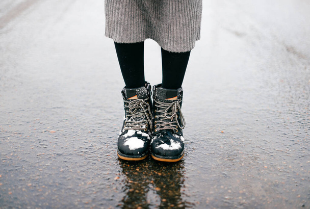 Cropped woman legs in boots standing on wet asphalt - Foto, afbeelding