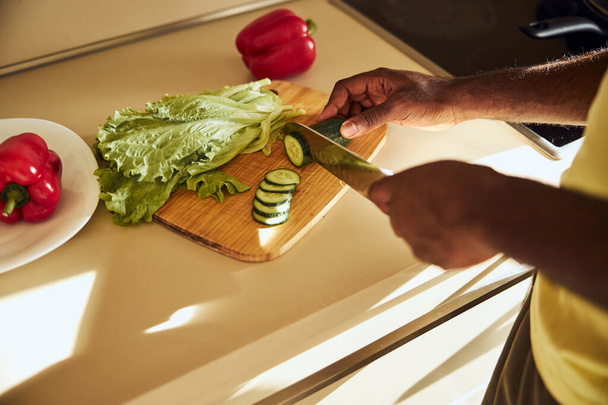Adult man making a cut to a green vegetable - Foto, afbeelding