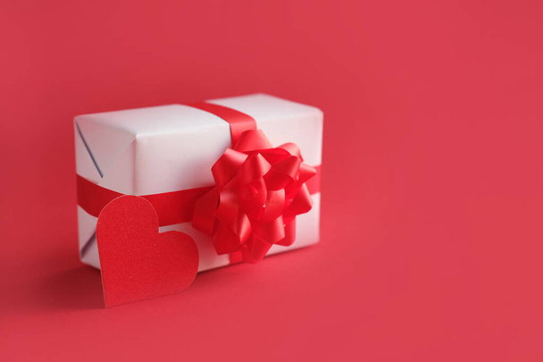 white gift box with a red bow on red background with copy space - 写真・画像