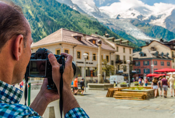 Touriste caucasien dans la soixantaine avec appareil photo numérique prenant des photos pendant ses vacances. Ville de Chamonix Mont Blanc, France. - Photo, image