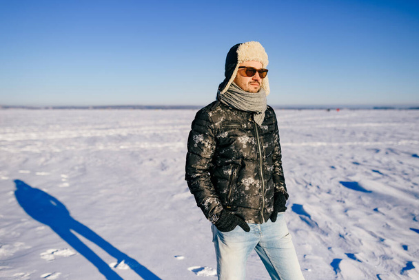 Dreaming stylish man in sunglasses posing in the snow field  - Foto, afbeelding