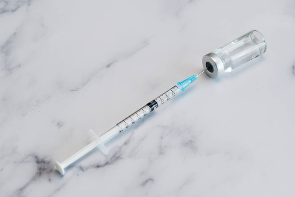 Jeringa médica y aguja para inyección hipodérmica en una encimera de mármol. - Foto, imagen