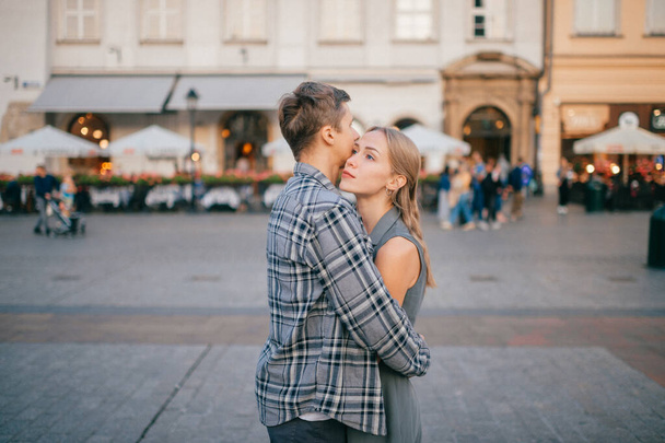 Young loving couple hugs at central square in Krakow (Cracow) - Foto, Imagen