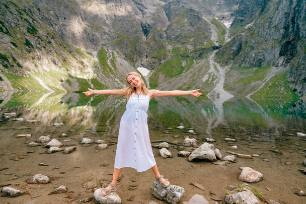 Funny girl with facial expression posing in white dress in lake with reflections under Mount Rysy in Polish Tatra - Φωτογραφία, εικόνα