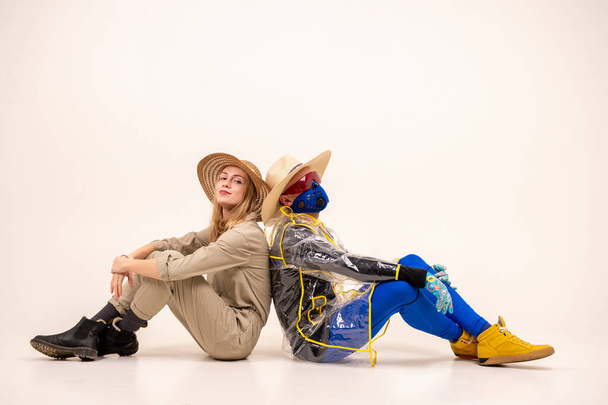 Stylish man in the mask and woman in straw hats posing over white background - Фото, зображення