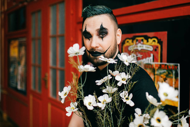 A portrait gothic black clown posing with flowers - Photo, image
