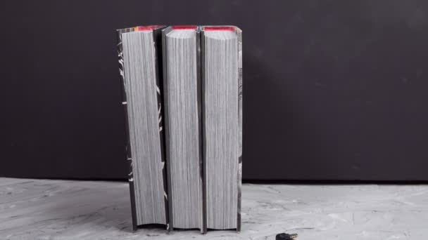 Fekete fülhallgató egy halom könyvvel. A hangoskönyvek és a modern oktatás fogalma - Felvétel, videó