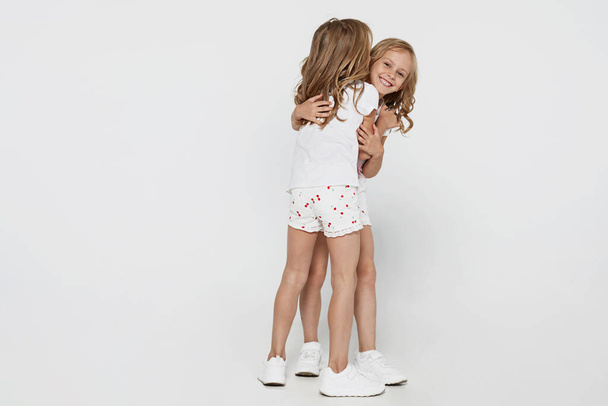 Смеющиеся маленькие девочки в белой одежде на белом фоне Детский студийный портрет. - Фото, изображение