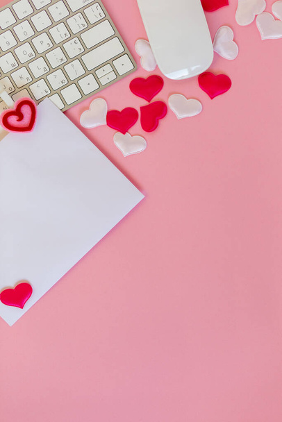 Write wish on white piece of paper for Valentines day on February 14. Celebrate Valentines day on pink background. Office flat lay with red toy hearts and white keyboard and mouse, love concept - Fotó, kép