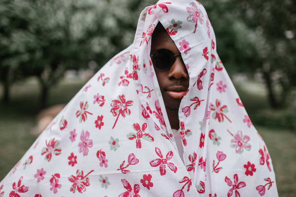 dark skinned man covered in printed sheet like arabian sheikh. Closeup portrait of african american male wearing funny costume - Photo, Image