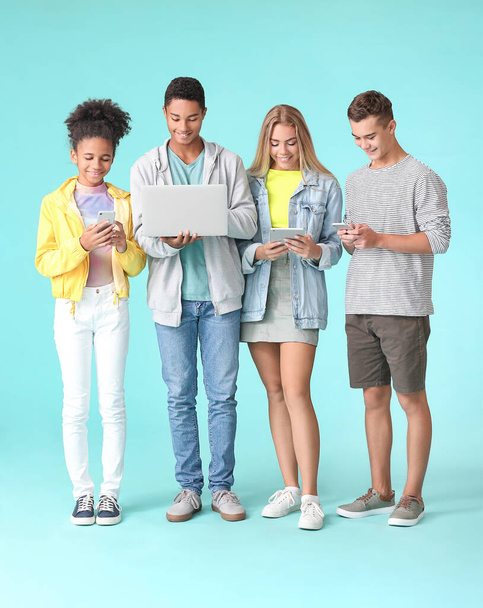 Teenagers with different devices on color background - Foto, Imagem
