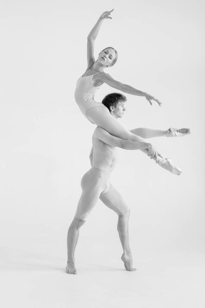 Young couple of modern ballet dancers posing over white studio background - Foto, afbeelding
