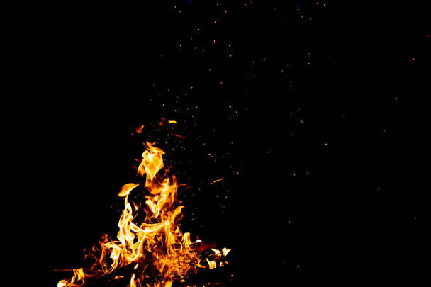Brennende Hölzer mit Feuerwerkskörpern, Flammen und Rauch. Seltsame merkwürdige elementare feurige Figuren auf schwarzem Hintergrund. Kohle und Asche. Abstrakte Formen bei Nacht. Lagerfeuer in der Natur. Stärke des Elements - Foto, Bild