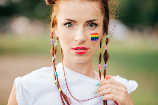 Red hair girl with lgbt gay pride flag on her face closeup portrait. - Foto, imagen