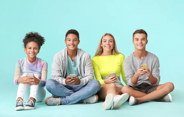 Teenagers with modern mobile phones on color background - Photo, Image