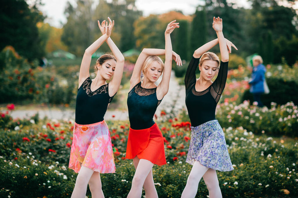 Three beautiful girls in colorful dresses posing outdoor. - Фото, зображення