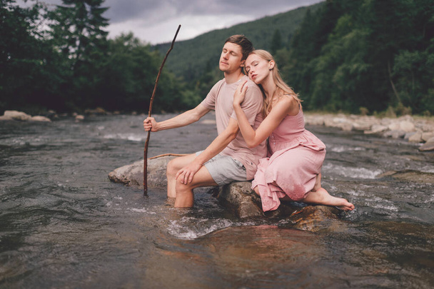 Lifestyle loving couple hugging at stone in the river. - Fotografie, Obrázek