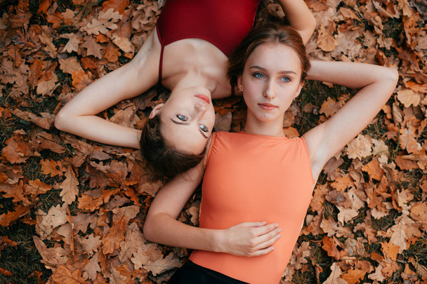 Two young girls lying on autumn leaves  - Foto, afbeelding