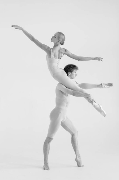 Young couple of modern ballet dancers posing over white studio background - Фото, изображение